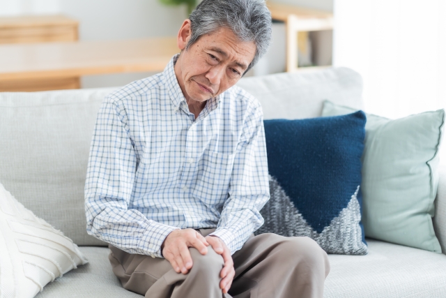 右ひざをおさえる男性の画像